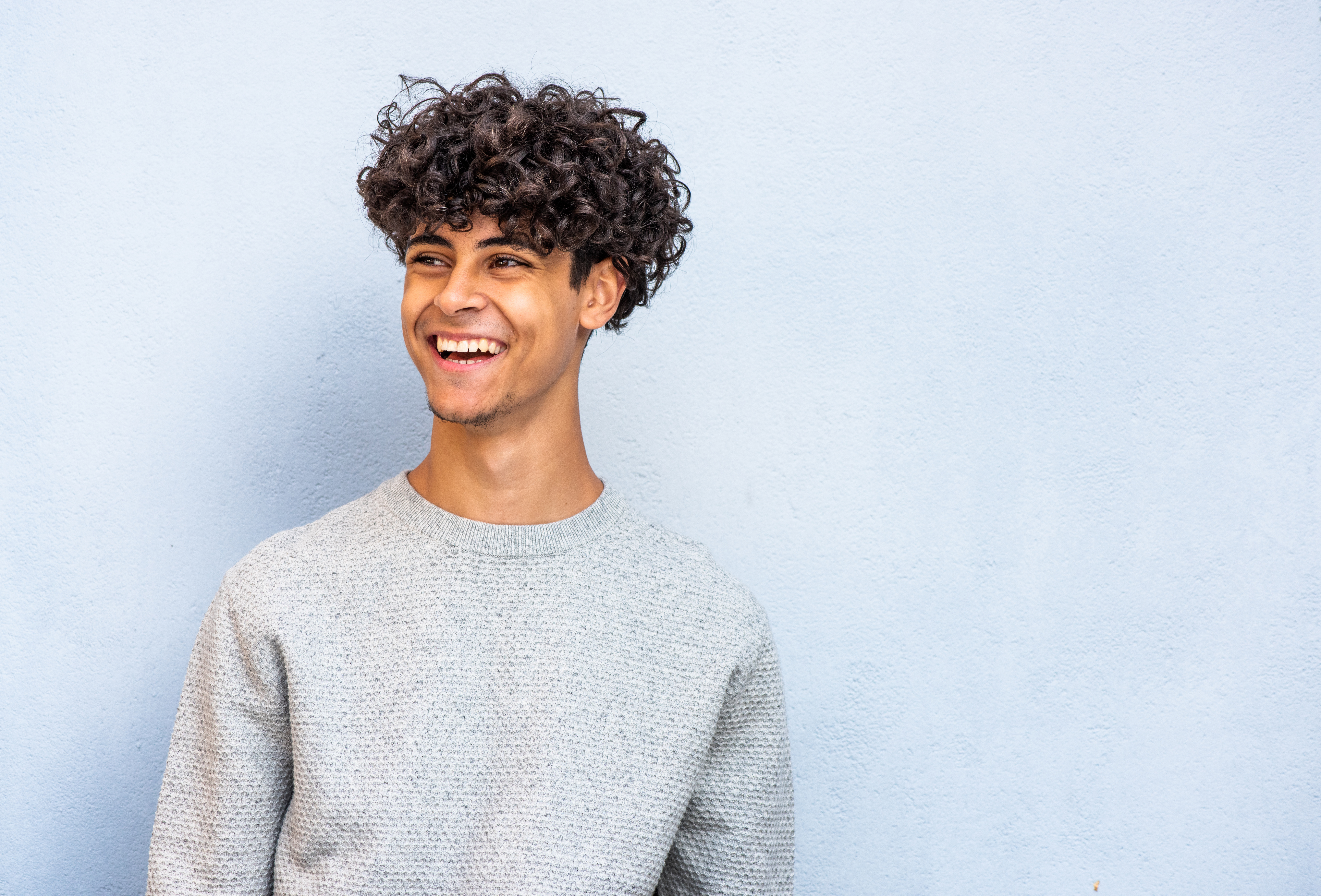 smiling young North African man by blue background