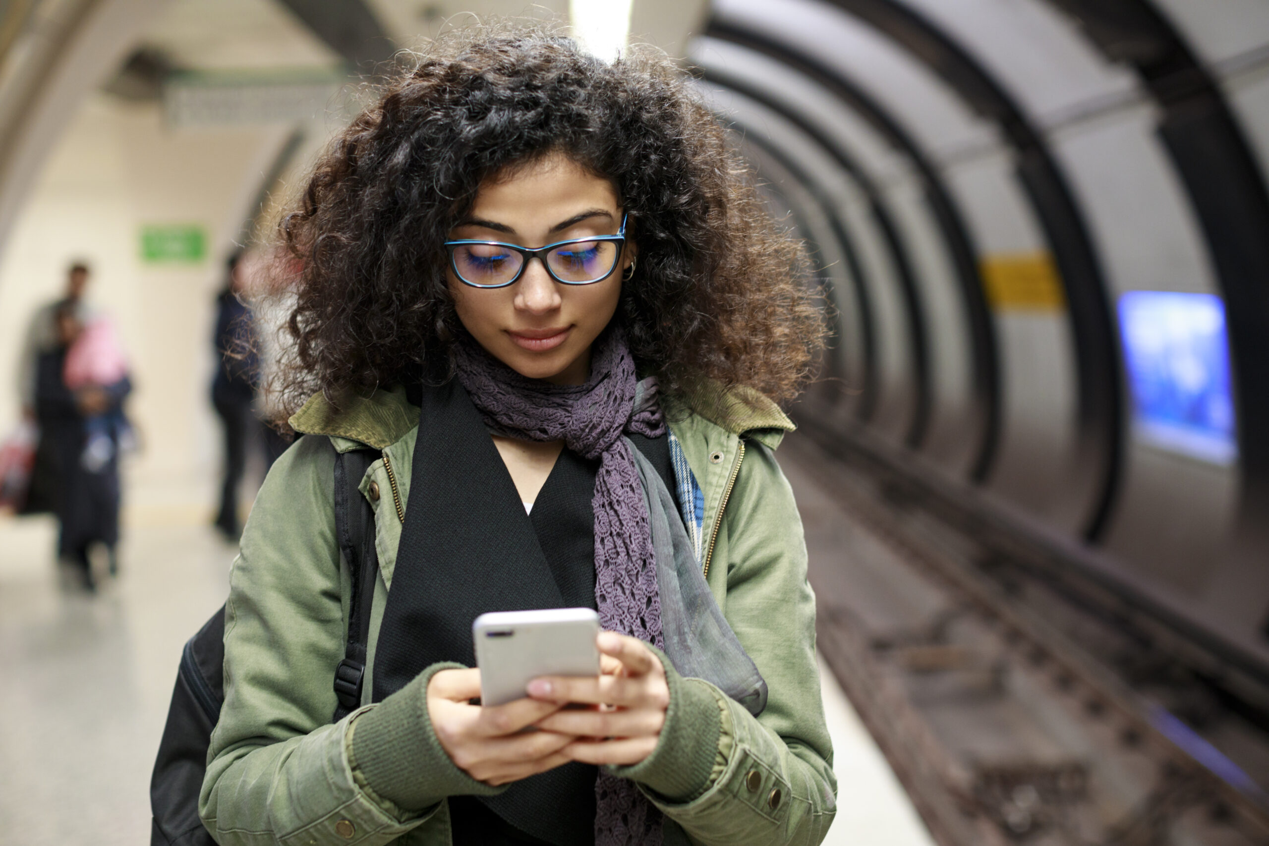 Young female commuter using mobile phone in the subway station